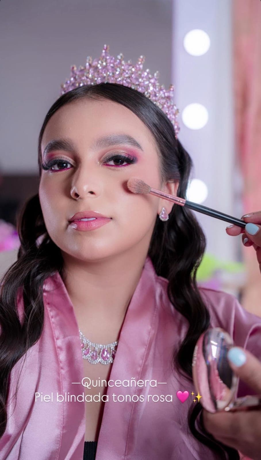 Quinceañera con corona rosa durante el maquillaje